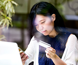 woman looking at phone and holding credit card