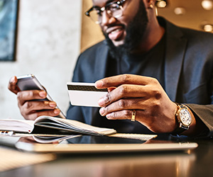 man looking at phone and holding card