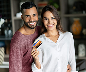woman and man posing and holding up credit card