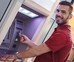 man putting card into ATM and smiling