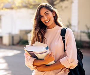 woman wearing backpack and holding books